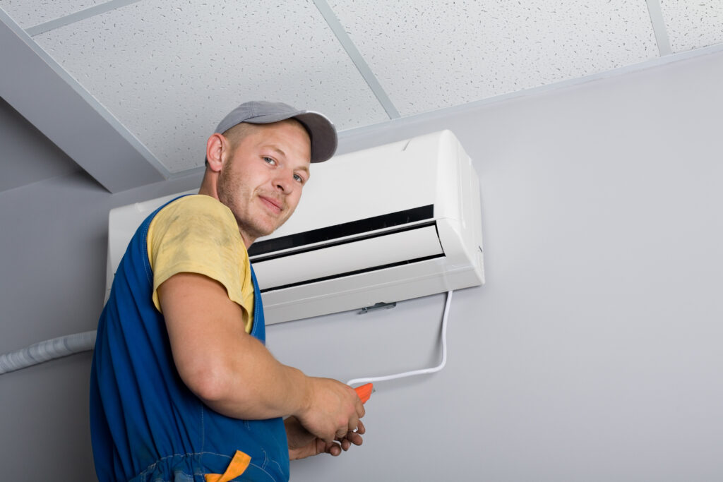 Young Setup Man Installs The New Air Conditioner In The Office. Young Setup Man Installs The New Air Conditioner In The Office.